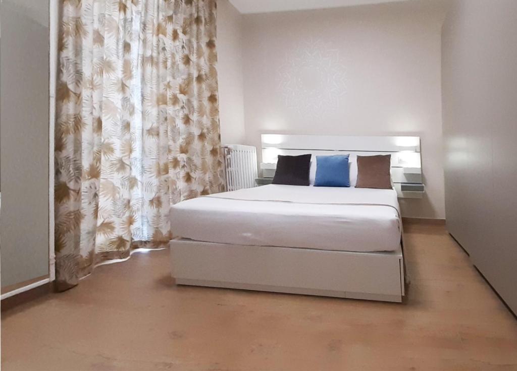 a bedroom with a white bed with blue pillows at REGINA ANNA HOME in Bari