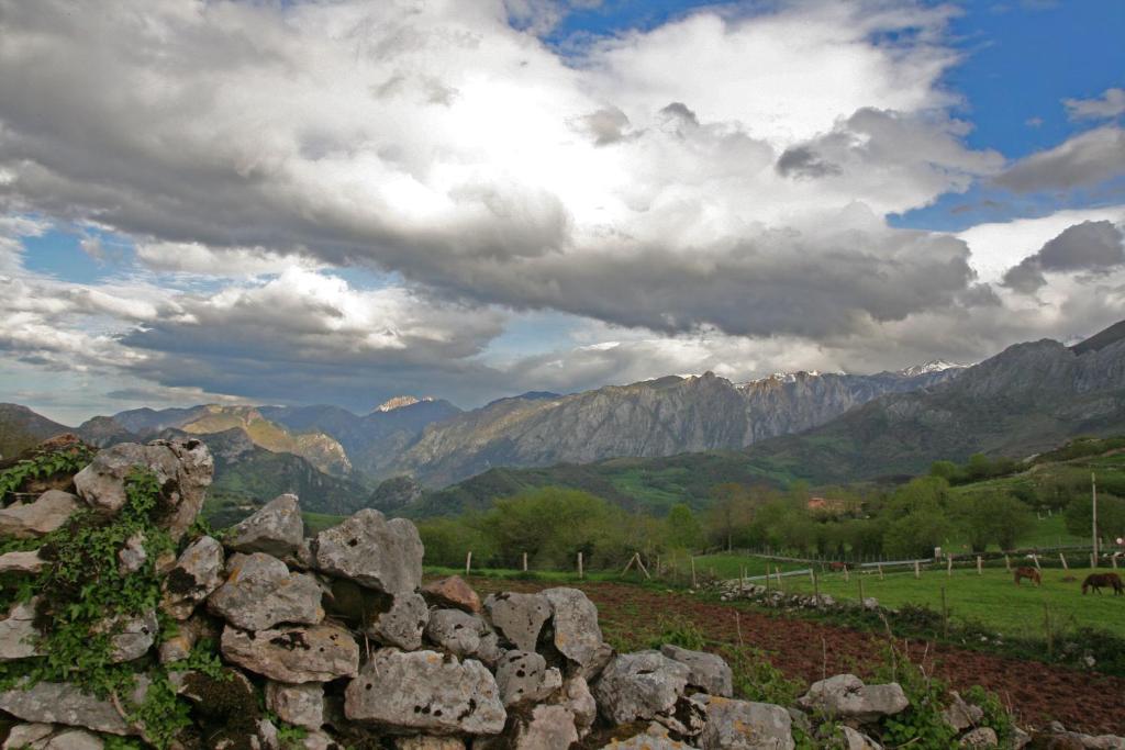 una pared de piedra con montañas en el fondo en El Patín de Monchu, en Pandiello