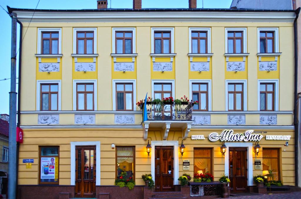 ein gelbes Gebäude mit Balkon davor in der Unterkunft AllureInn Hotel and Spa in Czernowitz