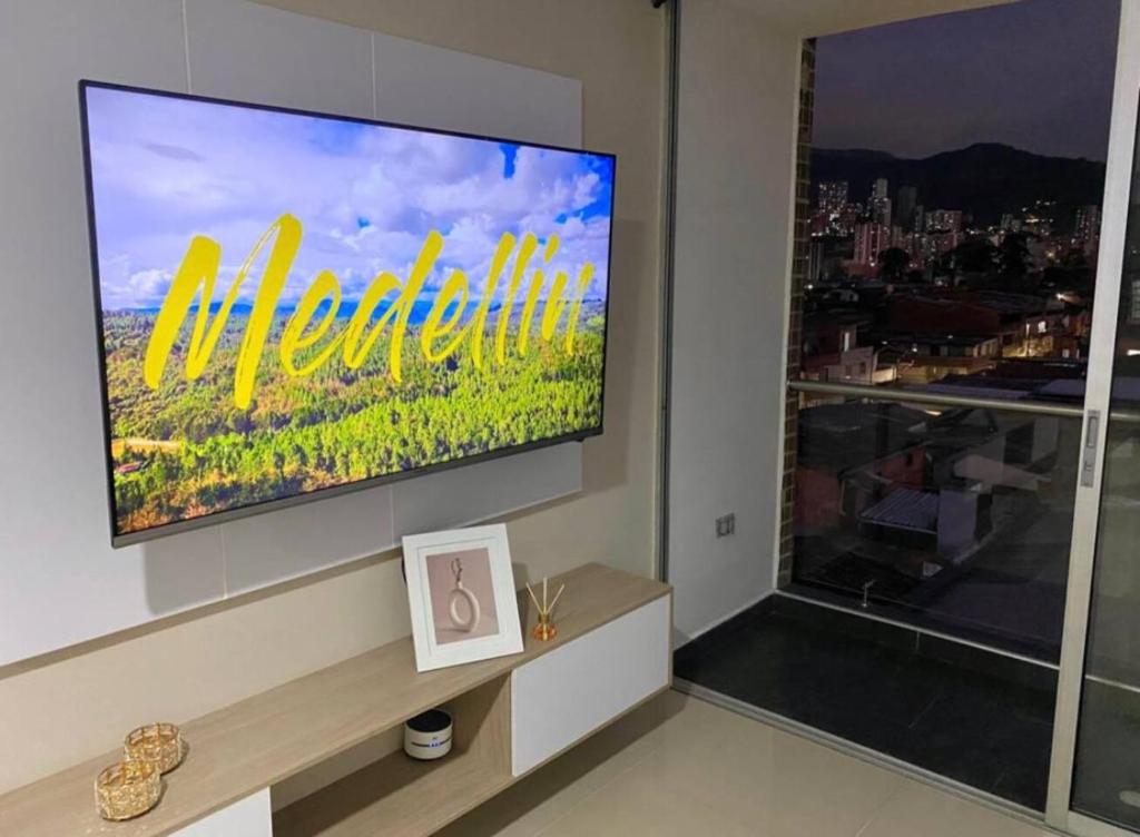 een grote televisie in een woonkamer met een raam bij de visita en Medellín, quédate aquí in Itagüí