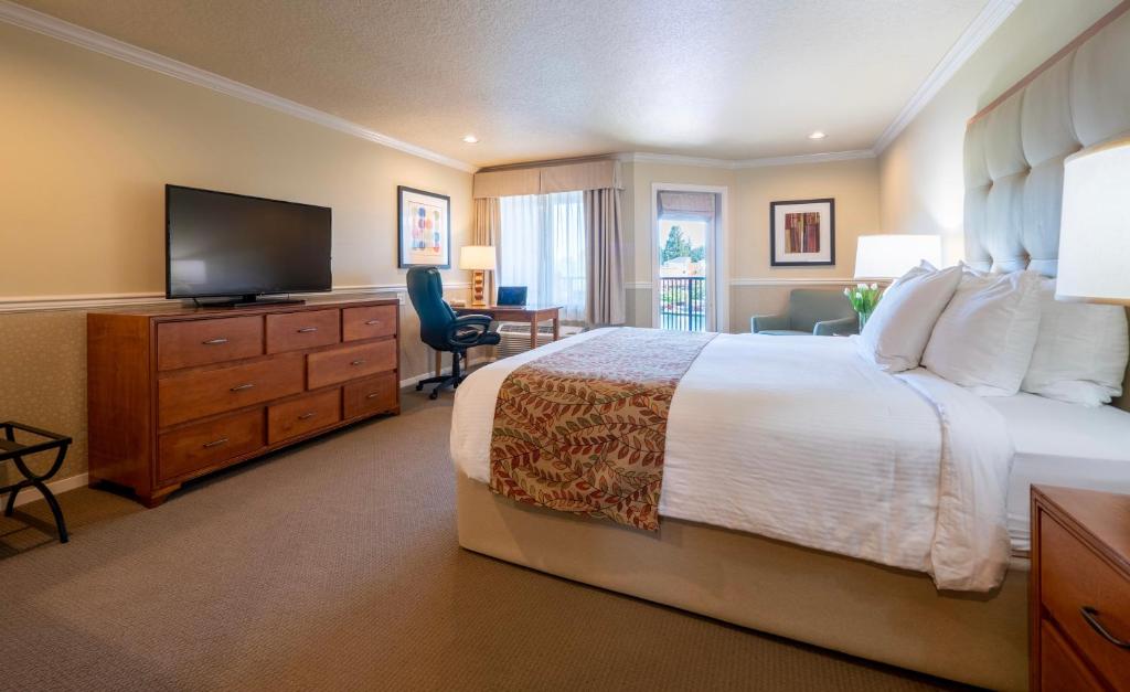 a hotel room with a bed and a flat screen tv at Century Hotel in Tualatin