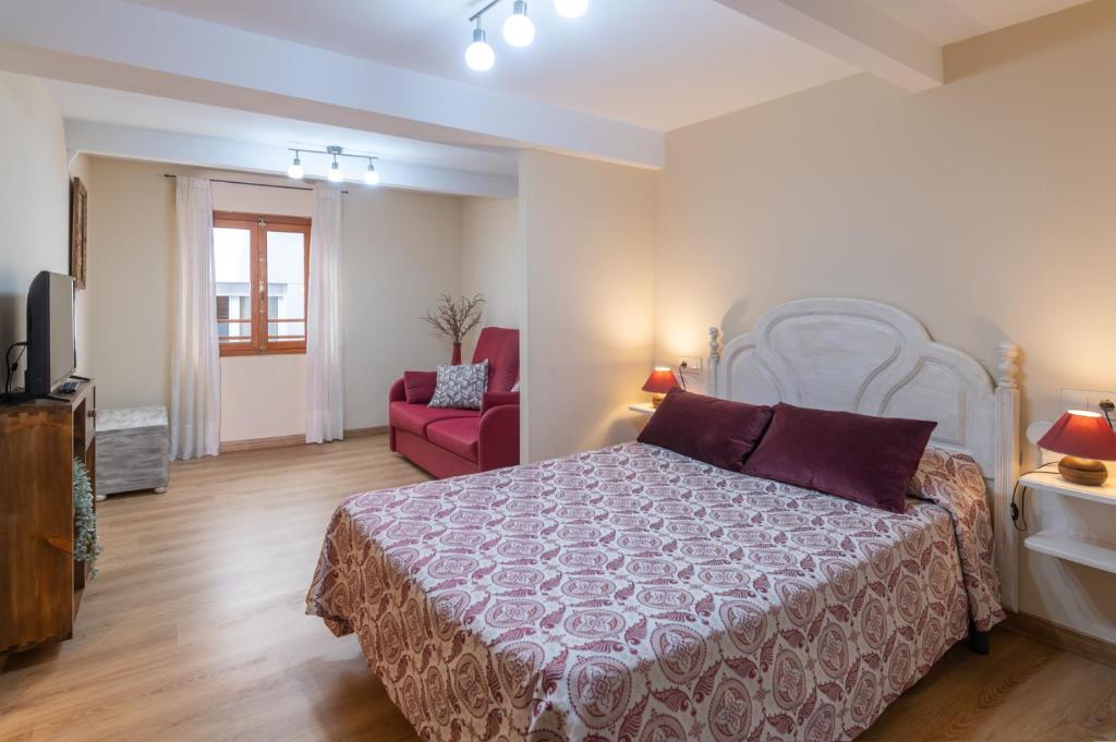 1 dormitorio con 1 cama y 1 silla roja en Belmonte, apartamento en Ribadesella, en Ribadesella