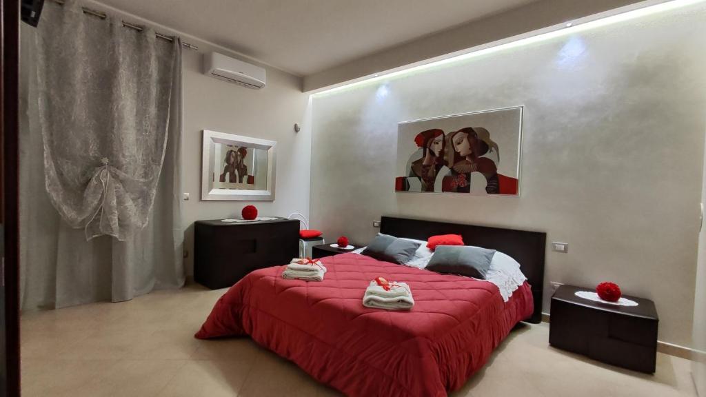 Il Giardino di Rosa في Sammichele di Bari: غرفة نوم بسرير احمر ولوحة على الحائط