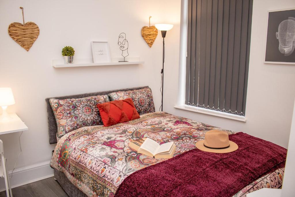 a bed with a hat and a book on it at Enchanting and welcoming space in Aintree
