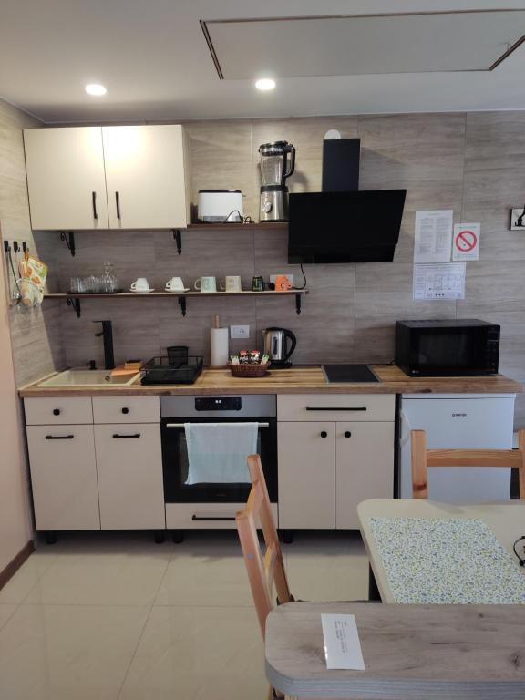 a kitchen with white cabinets and a stove and a table at Apartmani SLADJANA in Novi Sad