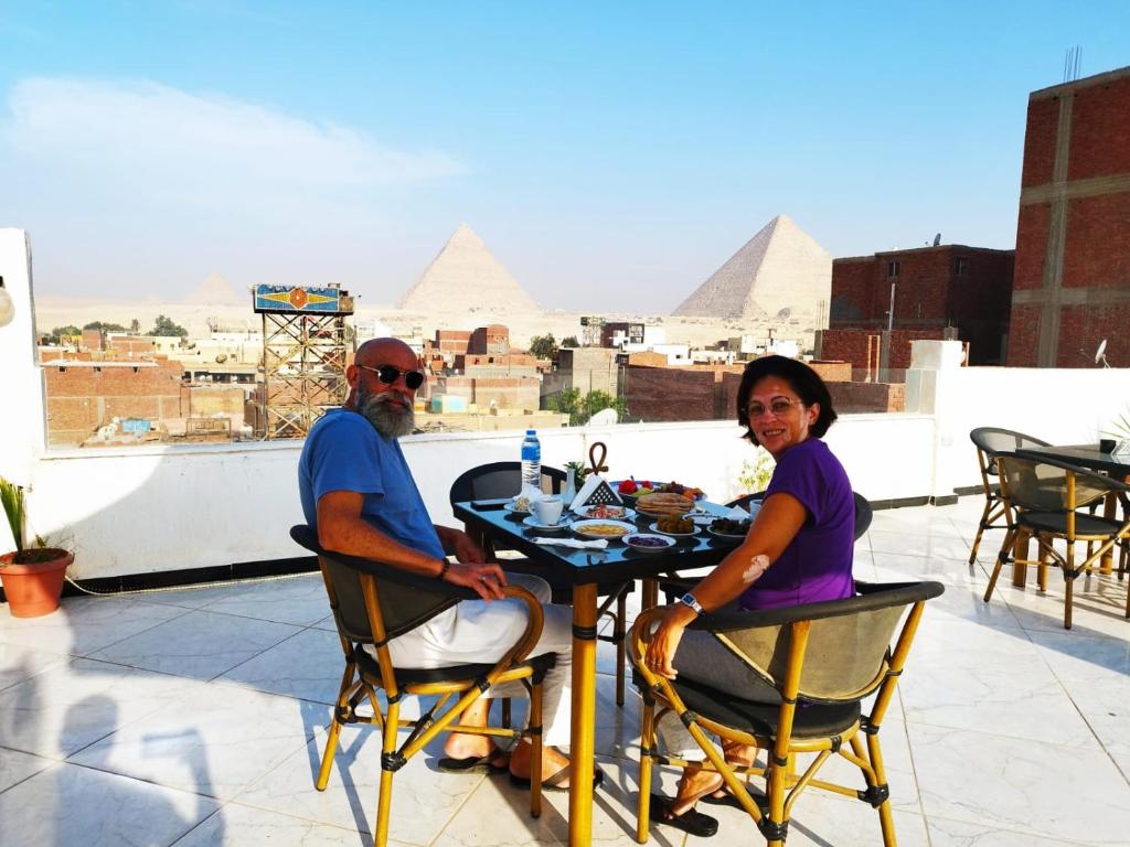 a man and woman sitting at a table with pyramids in the background at Eagles Pyramids View in Cairo
