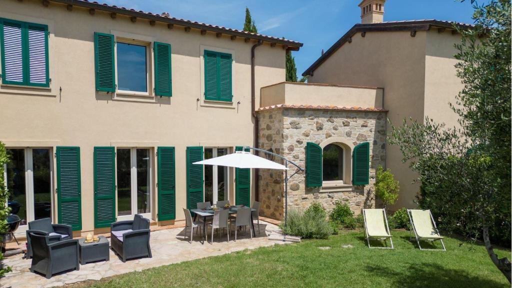 a patio with chairs and an umbrella in front of a house at Il Mirto in Gavorrano