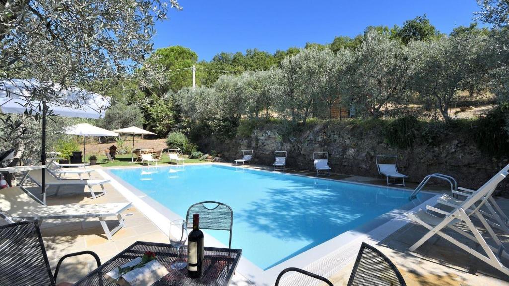 een zwembad met stoelen en een fles wijn bij Podere Le Coste in Loro Ciuffenna