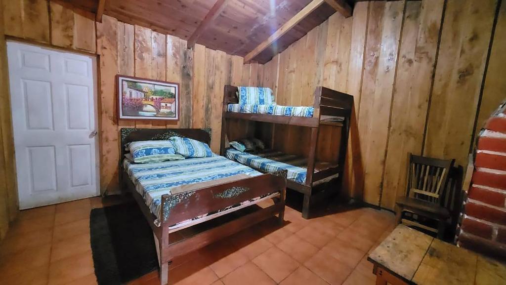 a bedroom with a bunk bed in a wooden room at Hotel de Montaña Buena Vista in Río Chiquito