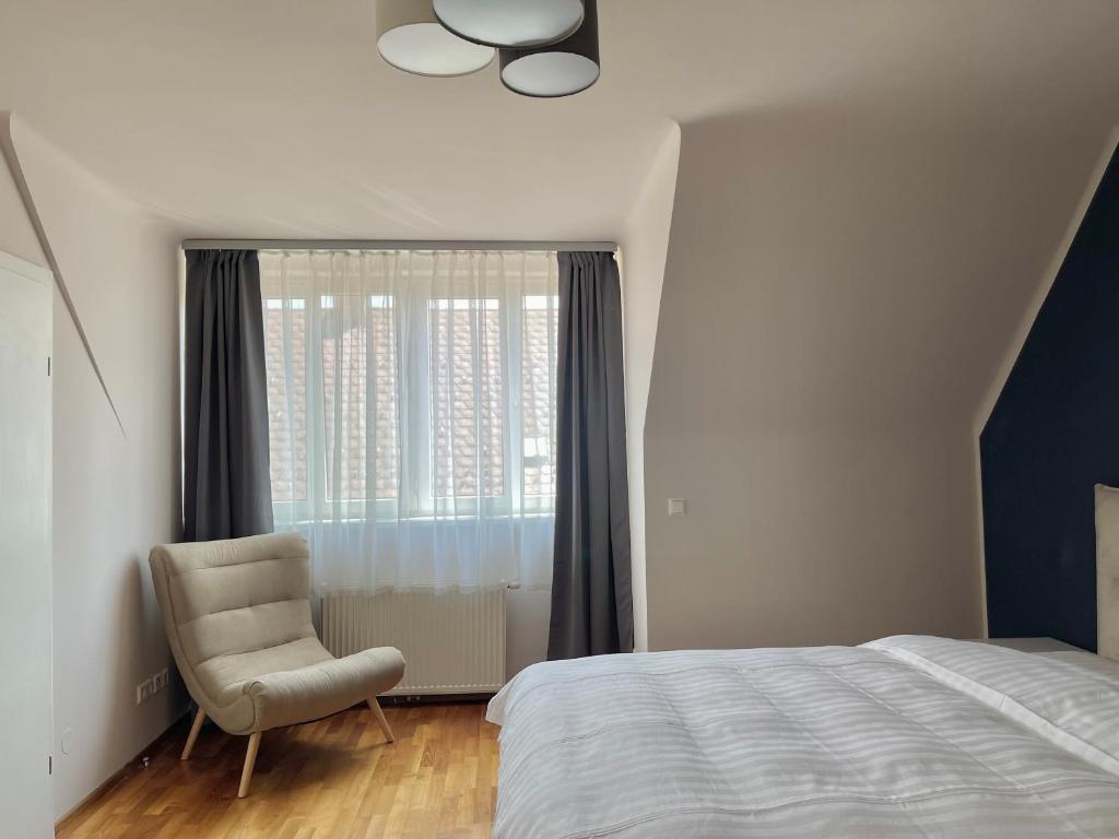 a bedroom with a bed and a chair and a window at Homely Stay Apartment 3 in Sankt Pölten