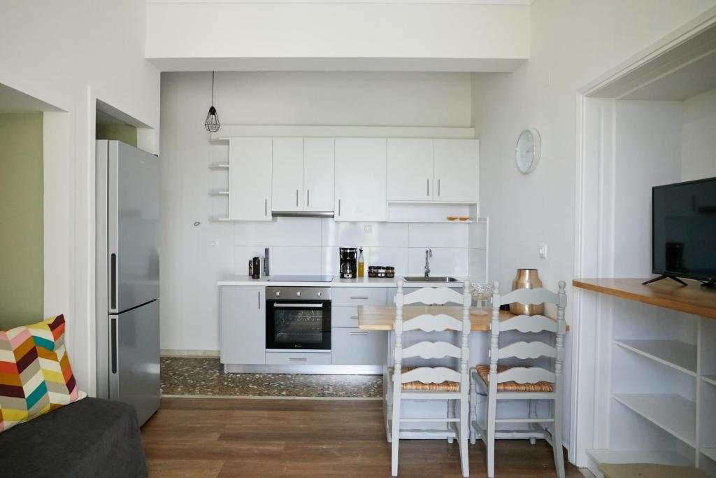 a kitchen with white cabinets and a table with chairs at Mosaic Luxury House in Chios