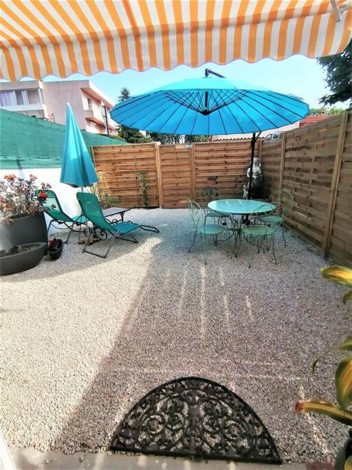patio con tavolo e ombrellone blu di T2 indépendant dans villa. a Le Pradet