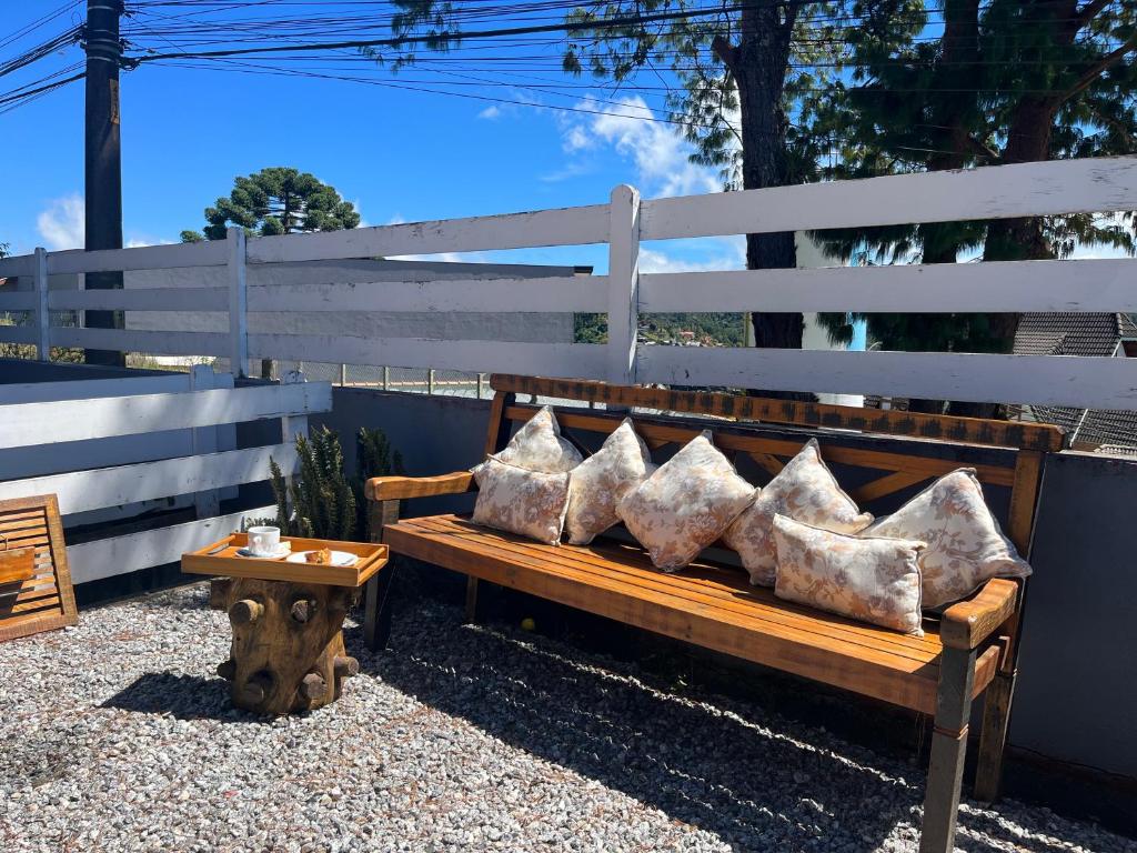 a wooden bench with pillows on it with a table at Pousada do Vento in Campos do Jordão