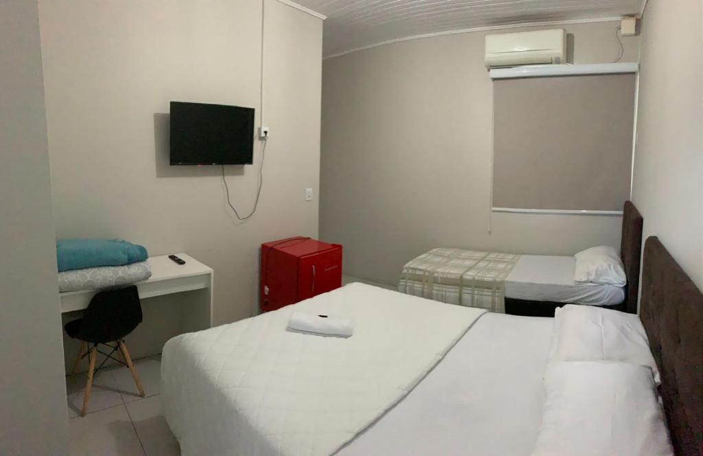 a room with two beds and a desk and a tv at HOTEL LIFE IJUI in Ijuí