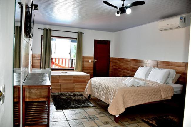 a bedroom with a bed and a bathroom with a window at Pousada Estrela Guia in Pirenópolis