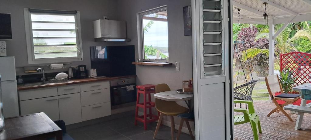 a kitchen with a table and chairs and a kitchen with a window at Beau F2 classé, vue mer, spa, jardin, bateau in Le Robert