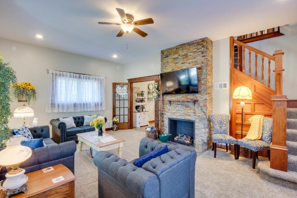 a living room with blue furniture and a stone fireplace at Central Chanute Historic Home with Porch! in Chanute