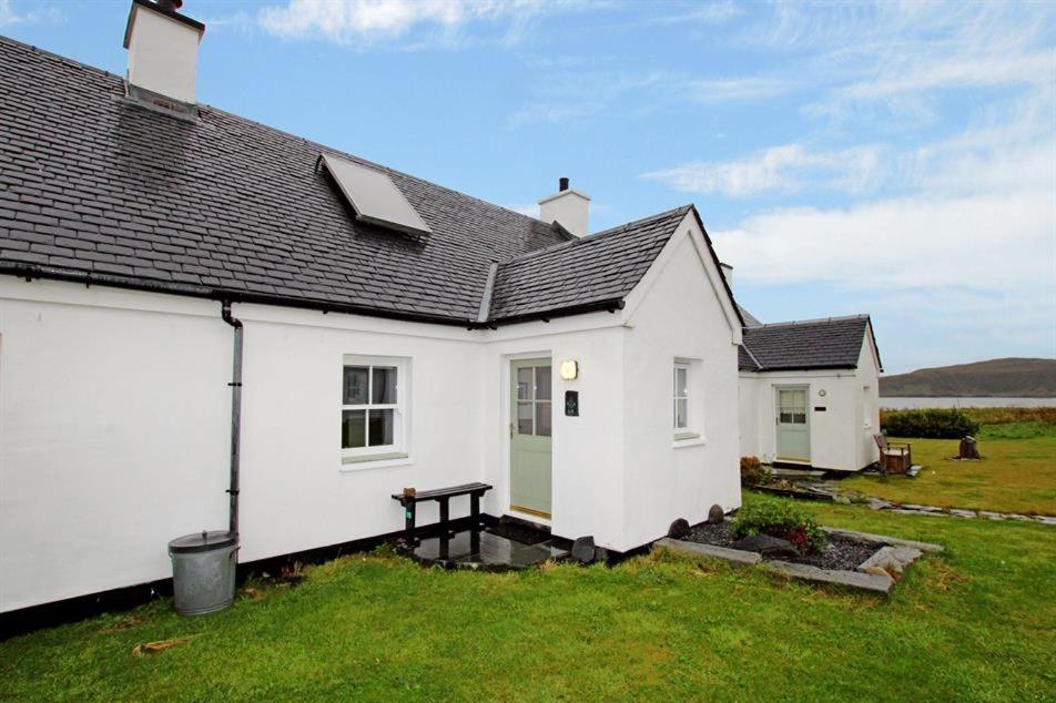 Biały dom z ławką na dziedzińcu w obiekcie Easdale Cottage w mieście Ellanbeich