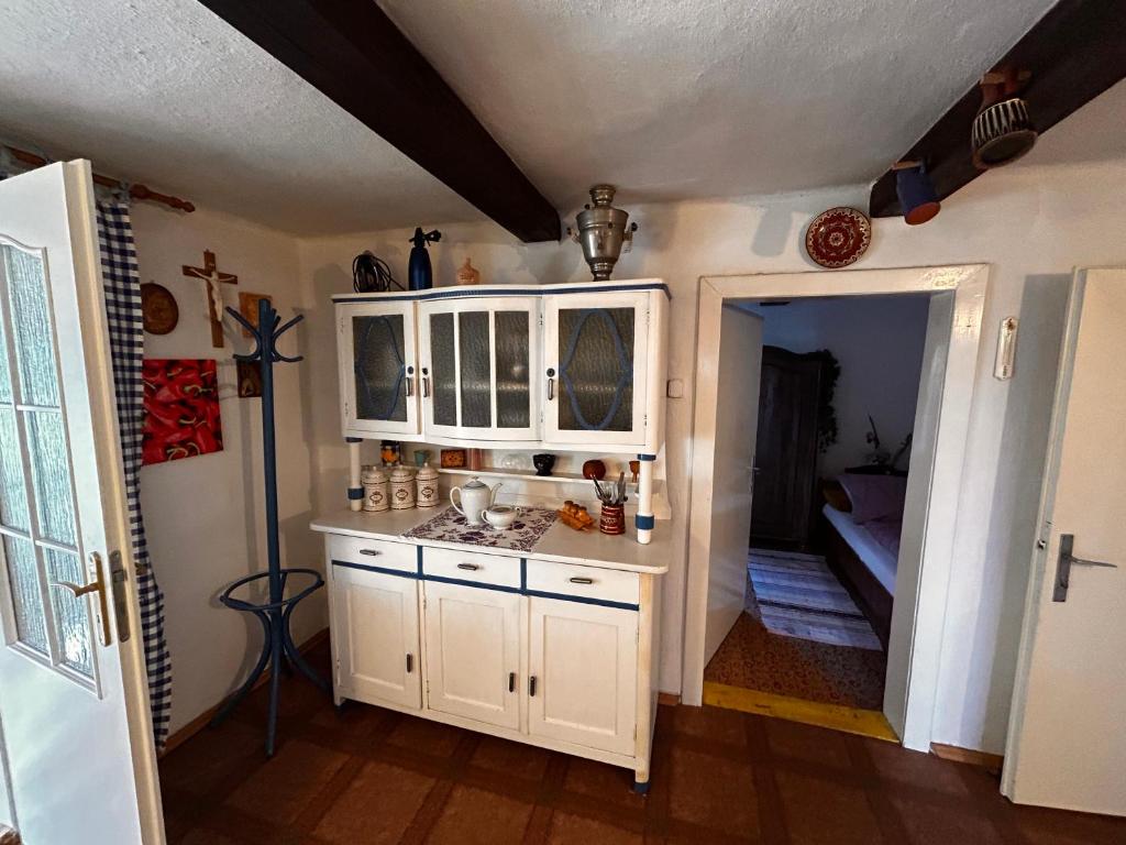 a kitchen with white cabinets and a room with a couch at Oáza klidu in Hrádek