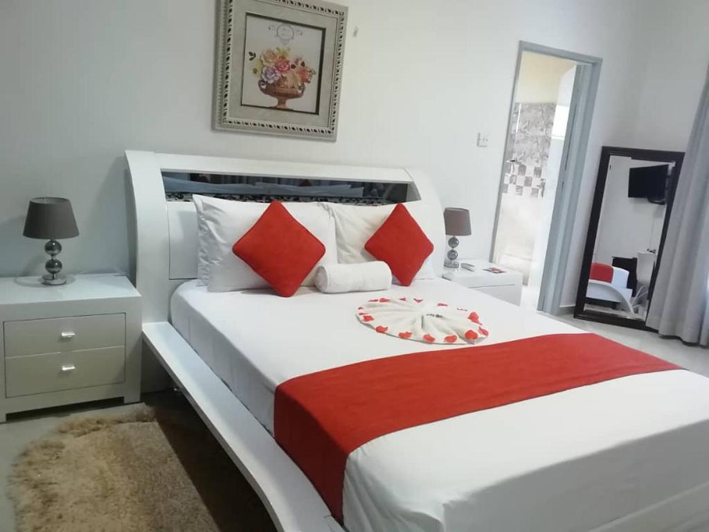 a bedroom with a large white bed with red pillows at Girlie's bed and breakfast in Kopong