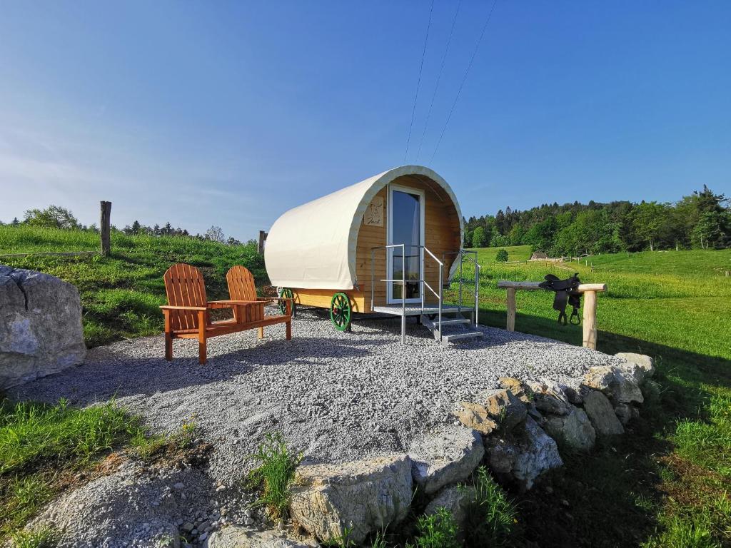a tiny house in a field with two chairs at Cowboy's Land in Višnja Gora