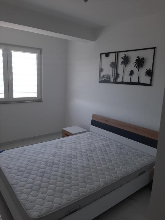 a white bedroom with a bed and a window at Apartman Tamara Struga in Struga