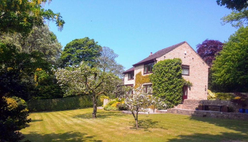 a large house with a yard with trees and grass at Maywalk House B&B in Eyam