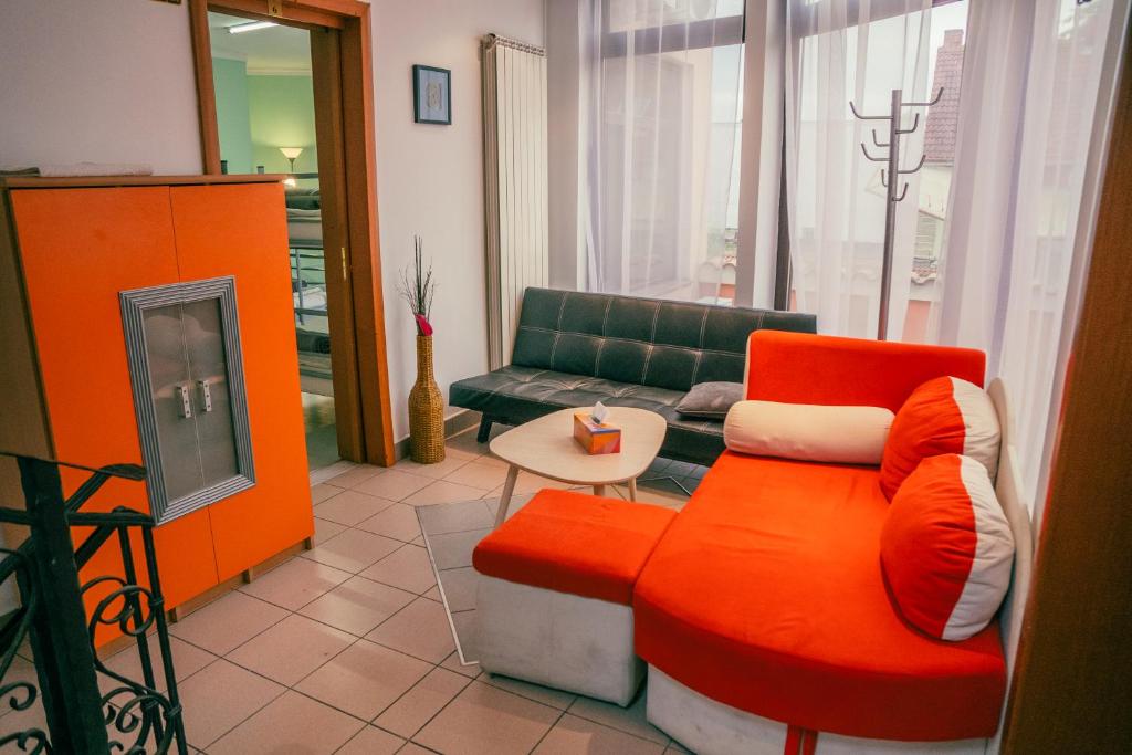 a living room with an orange chair and a couch at Central Hostel Partener in Oradea