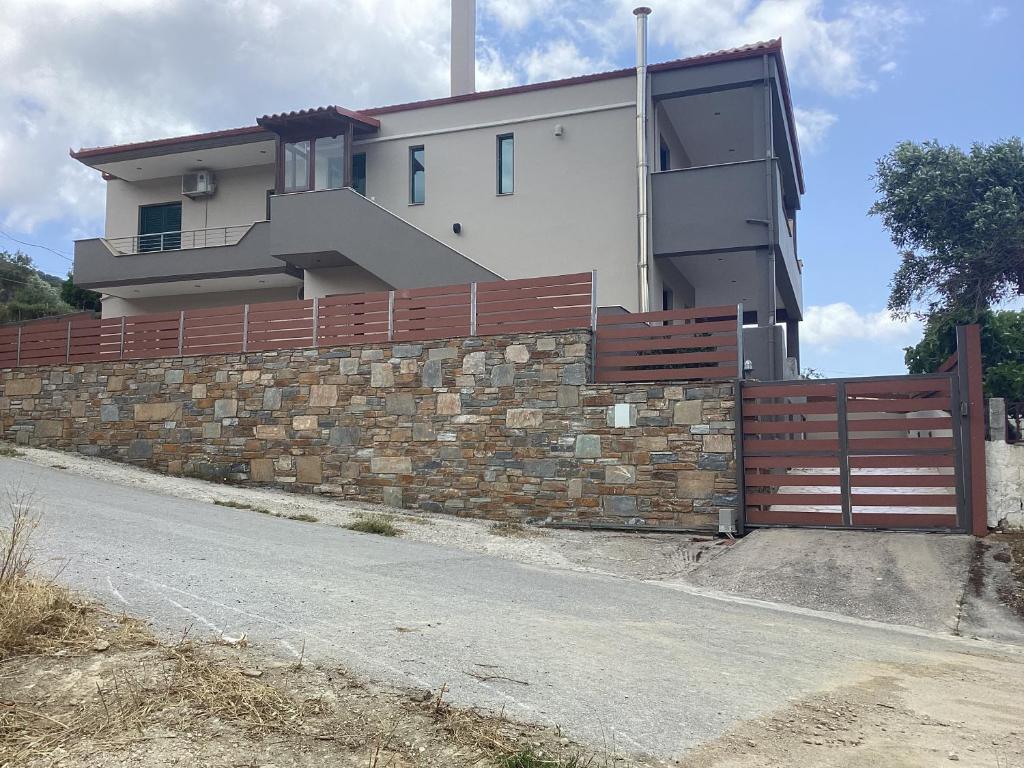 a house behind a brick wall with a fence at MARMARI Village in Ayía Marína