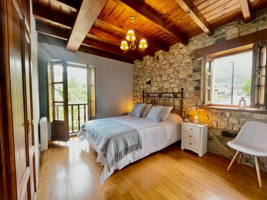 1 dormitorio con cama y pared de piedra en La Bolera Paraíso Astur en Llanes
