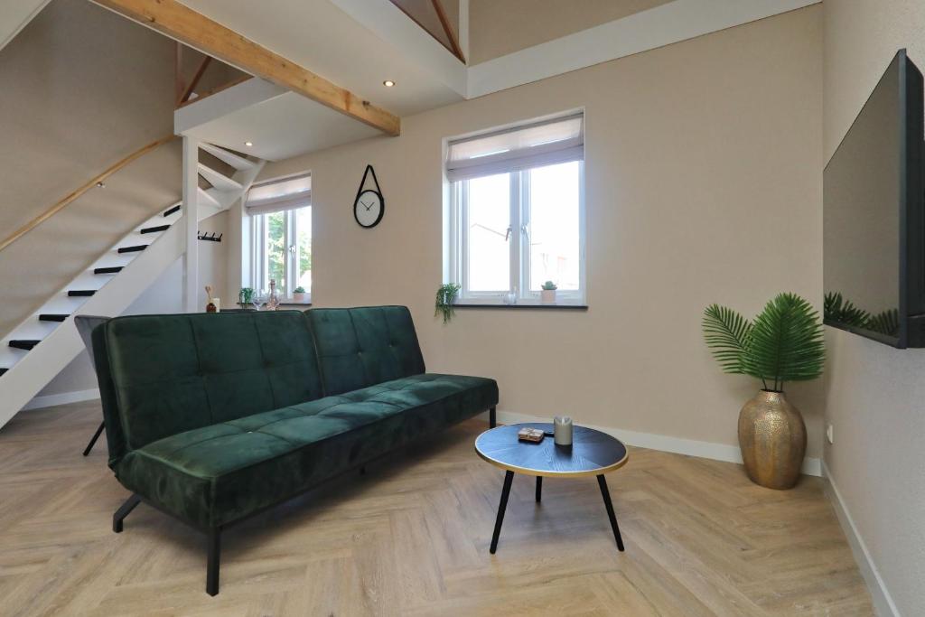 een woonkamer met een groene bank en een tafel bij appartement-gratis parkeren -bij strand en in het centrum in Noordwijk