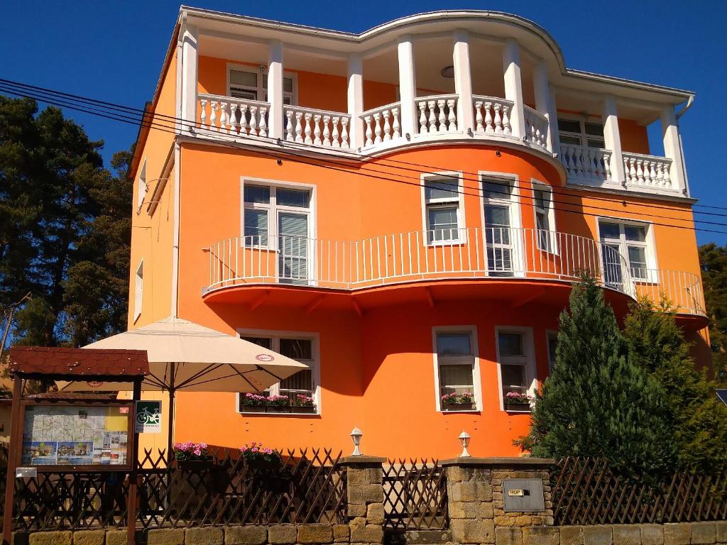 an orange building with a balcony and an umbrella at Pension Fami Retro Design in Staré Splavy