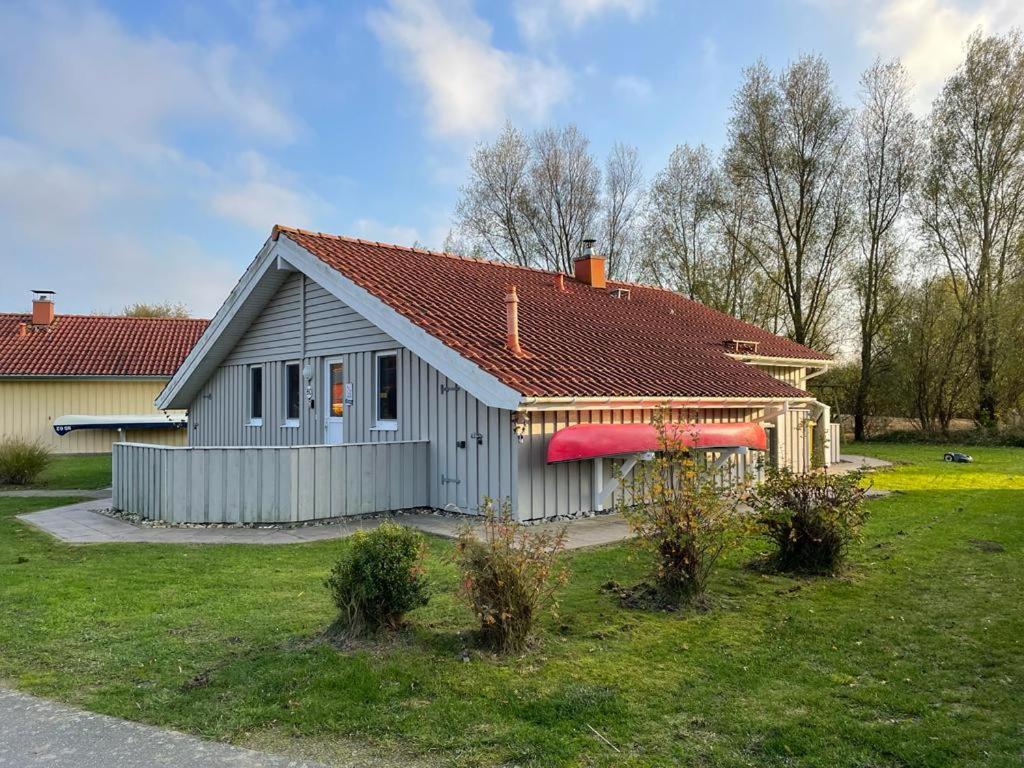 a gray house with a red roof in a yard at Nordseeperle-Ferienhaus in Otterndorf