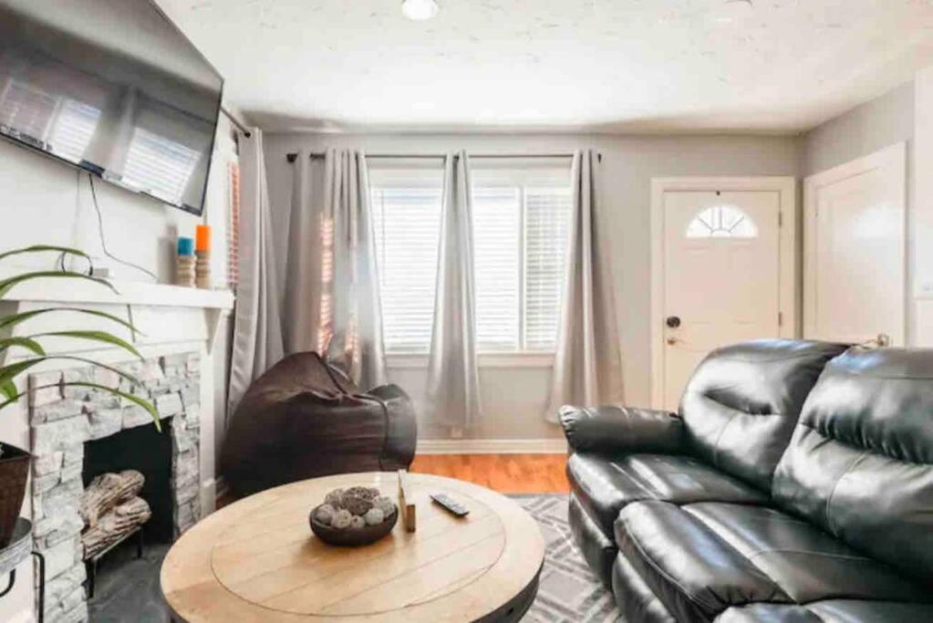 ein Wohnzimmer mit einer Ledercouch und einem Tisch in der Unterkunft Charming Farmhouse Retreat near Downtown & University Modern Amenities, Fireplace & Porch! in Birmingham