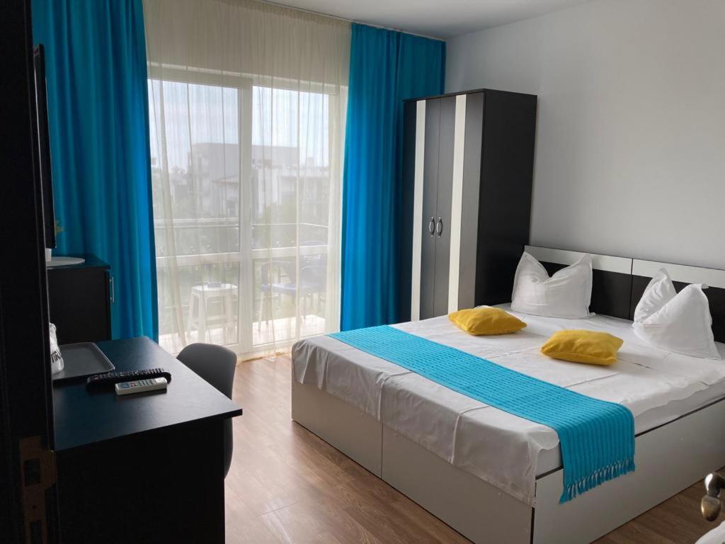 a bedroom with a bed with blue curtains and a desk at Vila Sofia in Eforie Nord