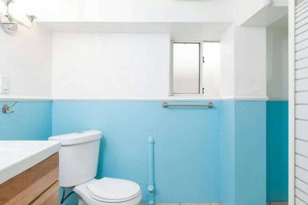 baño con paredes azules, aseo y lavamanos en Vancouver 2BR Garden Suite en Vancouver