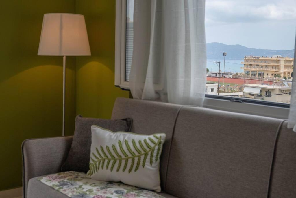 uma sala de estar com um sofá e uma janela em Πράσινη πινελιά διαμέρισμα em Kissamos