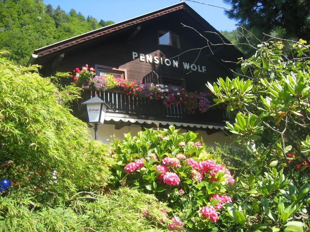 ein Gebäude mit einem Balkon mit Blumen darauf in der Unterkunft Pension Wolf in Steindorf am Ossiacher See