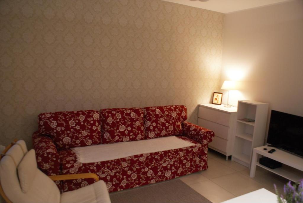 a living room with a red couch and a tv at Apartament Alma in Gdańsk