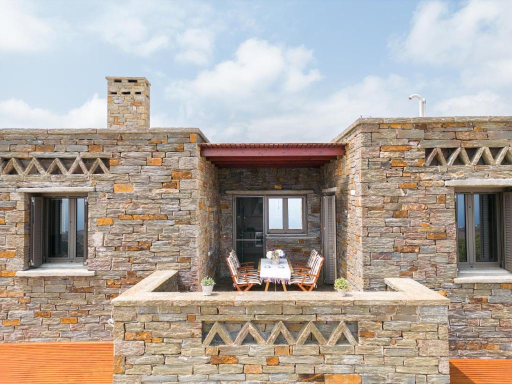 uma casa de pedra com uma mesa e cadeiras num pátio em Stone Pearl Kea em Elliniká