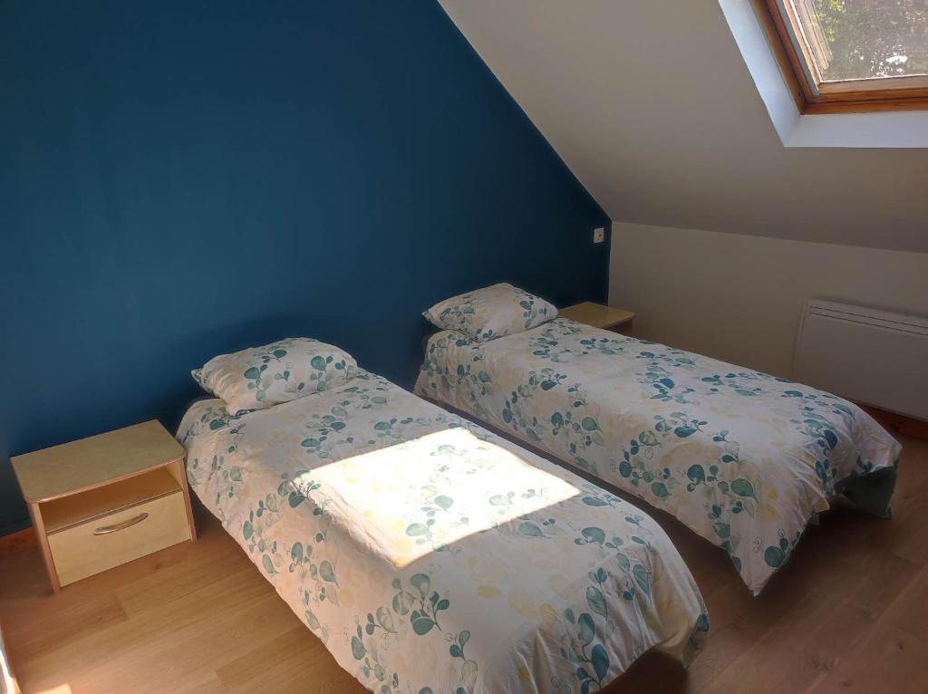 two beds in a bedroom with a blue wall at La petite trapue in Desvres