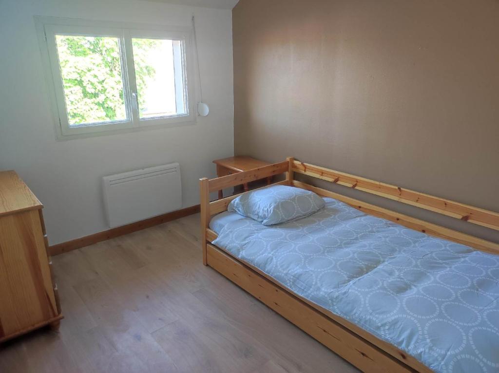 a bedroom with a wooden bed in a room with a window at La petite trapue in Desvres
