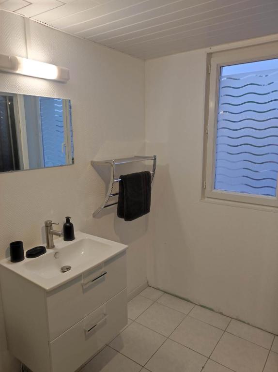 a white bathroom with a sink and a window at La petite trapue in Desvres