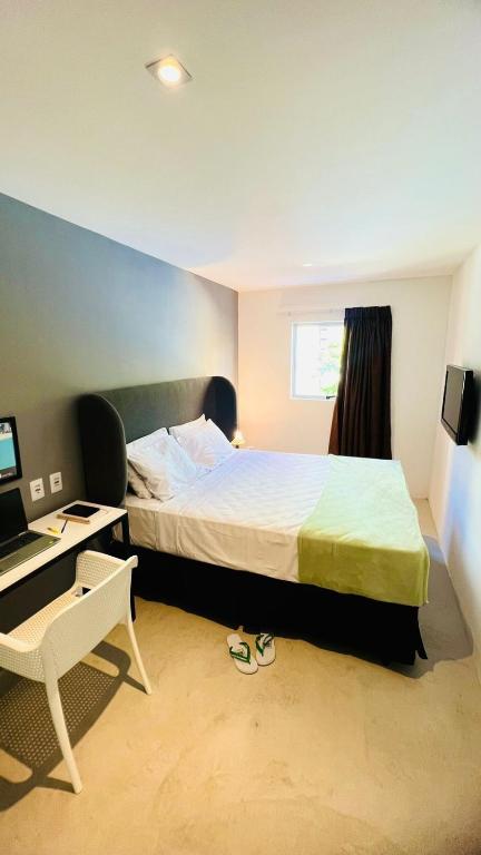 a bedroom with a bed and a desk with a computer at URB Hotel in Fortaleza