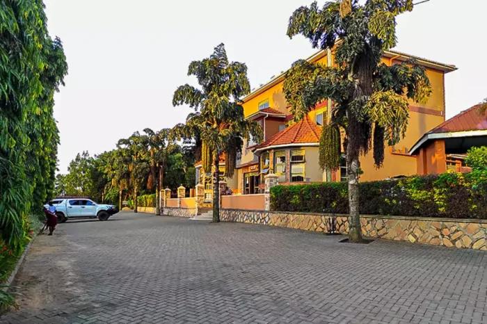a street in front of a house with a car at Conbary Hotel in Wakiso
