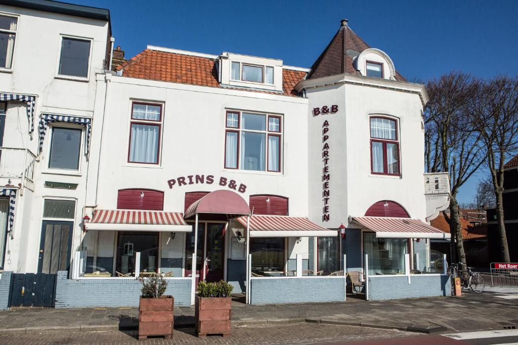 ein weißes Gebäude mit rotem Dach in der Unterkunft Prins Appartementen in Egmond aan Zee