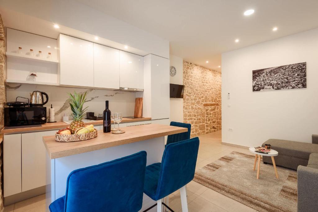 a kitchen and living room with a counter and blue chairs at Apartmani Boras in Metković