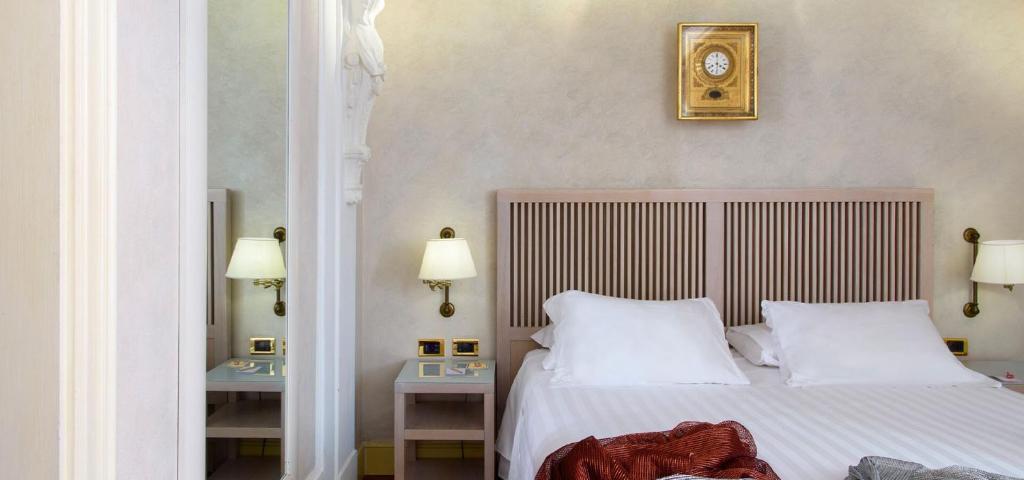 a bedroom with a bed with two tables and a clock on the wall at Art Hotel Orologio in Bologna