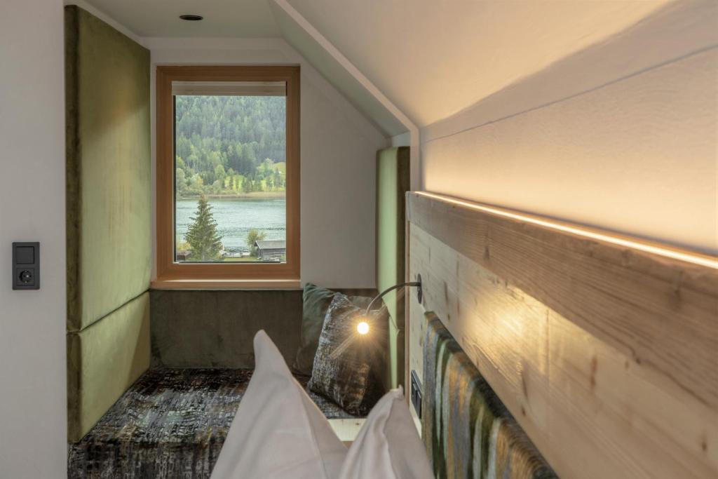a room with a window and a bench with a view at Hotel Winkler-Tuschnig in Weissensee