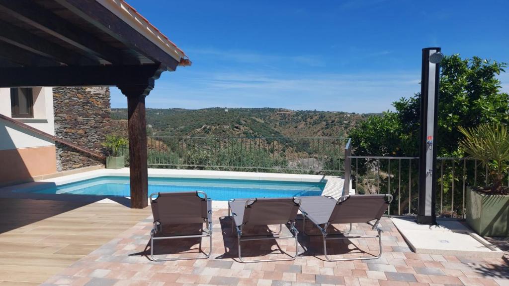 a patio with three chairs and a swimming pool at Casalagata in Alcántara